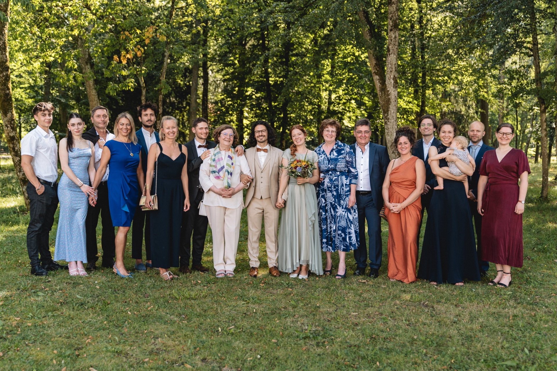 Gruppenfoto der Hochzeitsgesellschaft auf der Wiese im Park