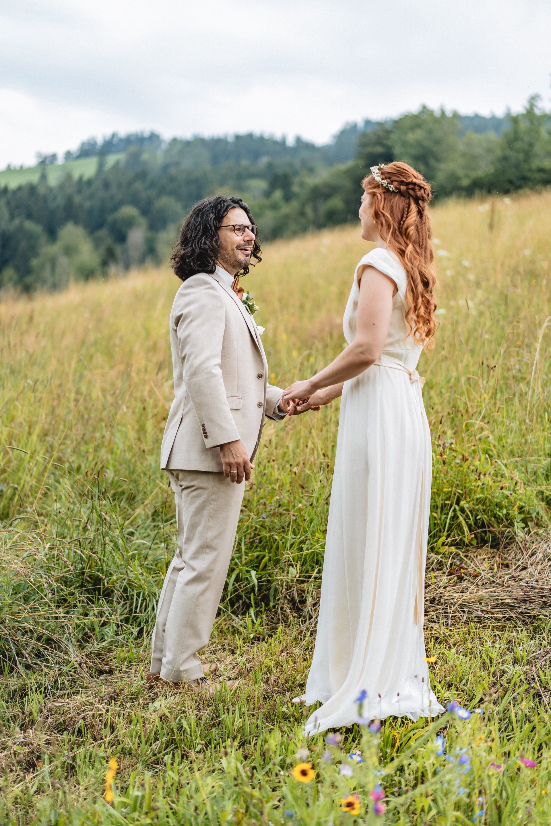 Hannah und Alexis halten sich beim First Look an den Händen, Voralpen im Hintergrund